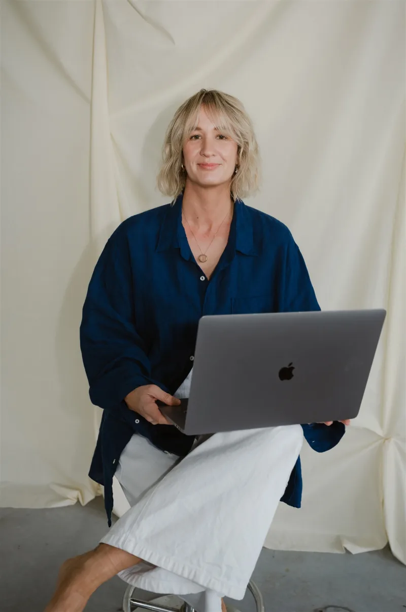 Ash in a navy shirt, laptop open in front of her